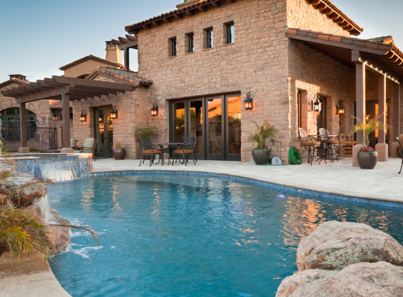 A pool in the backyard of a house with a waterfall 1